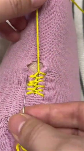 stitching the purple socks precisely using a professional manual yellow thread sewing needle