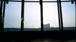 Tracking of unrecognizable businesspeople with briefcase and suitcase walking along hall of building with panoramic windows