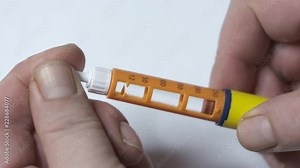 Insulin therapy routine. Patient with diabetes using diabetic insulin pen for self-injection. Removing protective pull tab from the needle and checking the dose before injecting.