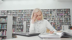 Stressed female student studying intensely at the library