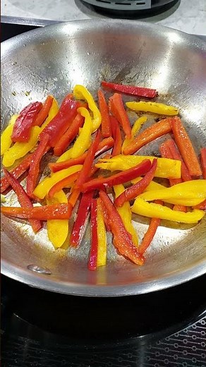 Red and yellow bell peppers grilling in the pan on the stove top