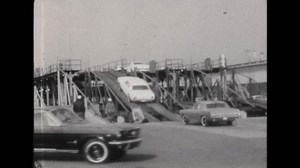 1950s: Ford cars drive up ramp and park in a row.