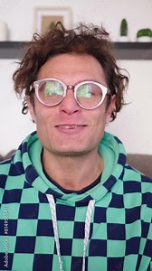 Vertical. Caucasian adult science communicator recording video tutorial in living room home. American nerdy man looking at camera. Influencer uploading content to social networks. Geeky with glasses.