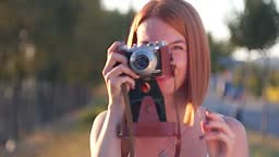 Smiling young redhead taking a photo of you with a vintage camera...
