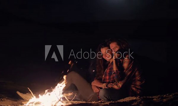 Romantic Couple Cuddling by a Campfire on the Beach at Night