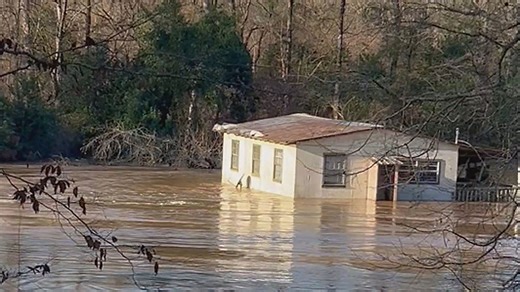 Floating house drifts past resident during Mississippi flooding