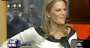 Newswoman bending over in a black leather skirt