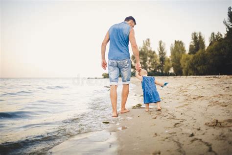 Papá Enseña Paseos De Su Pequeña Hija Sosteniendo Su Mano En Una Playa