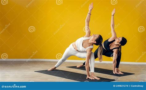 Young Attractive Women Practicing Yoga Lesson With Instructor Standing Together In