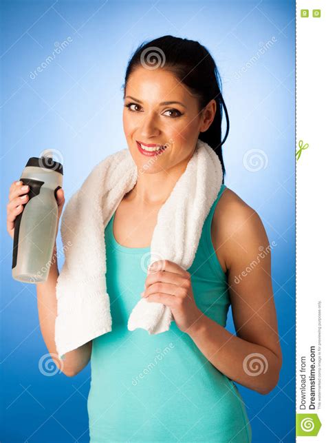 Woman Rests After Fitness Workout With Towel Around Her Neck Drinking