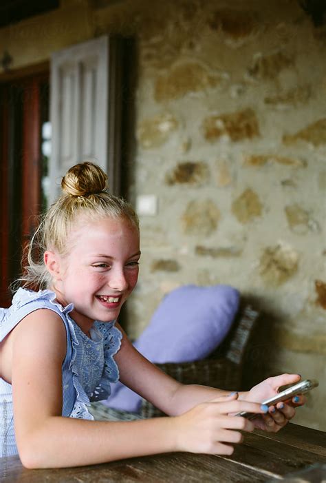 Preteen Girl Laughing While Holding Her Mobile Telephone By Stocksy