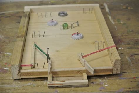 A Wooden Board With Several Pieces Of Wood And Pins Sticking Out Of It