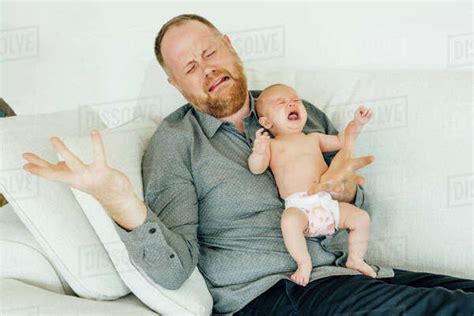 Portrait Of Crying Father Holding Crying Baby Daughter Stock Photo