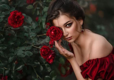 Beautiful Woman In Red Dress Walking In The Garden Full Of Roses Stock