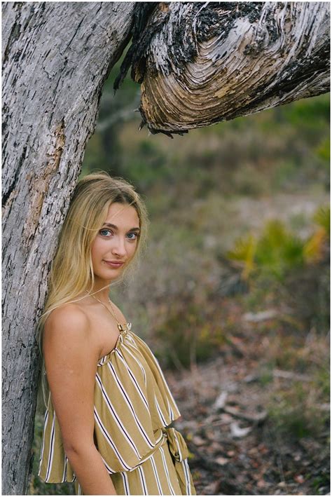 A Beautiful Blonde Woman Standing Next To A Tree