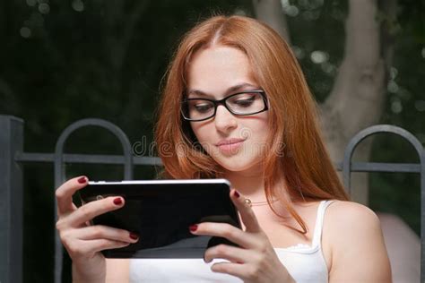 有一台片剂个人计算机的美丽的年轻红头发人妇女在倾斜使用触摸屏幕的公园 库存照片 图片 包括有 生活方式 倾斜 42043176