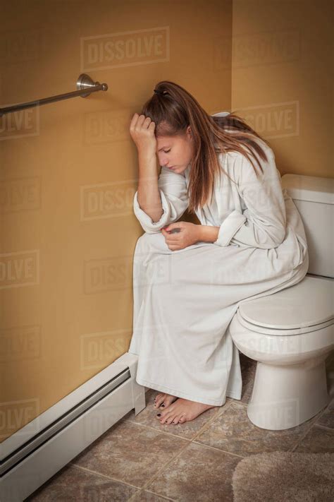Teenage Girl Sitting In The Bathroom On The Toilet Seat Looking Unhappy