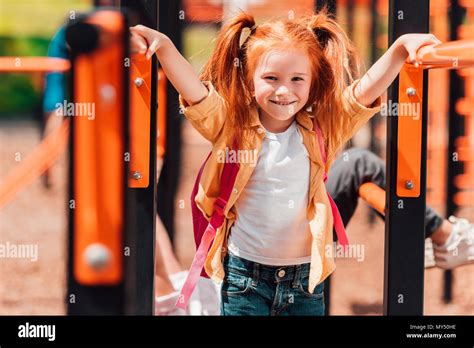 Adorable Redhead Girl Smiling At Camera While Playing On Playground