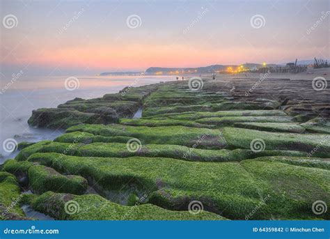 Sunrise By A Peculiar Rocky Beach With Dramatic Dawning Sky Stock Photo