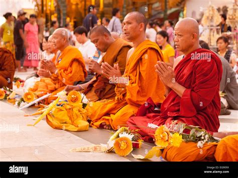 A Group Of Buddhist Monks Praying And Meditating At Sunset Shwedagon