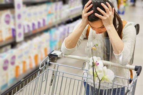 Woman With Shopping Cart In Supermarket Holding Her Head Stock Photo