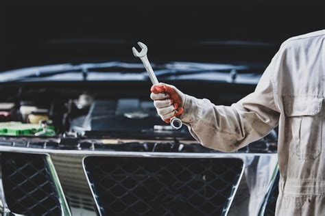 Car Repairman Wearing A White Uniform Standing And Holding A Wrench