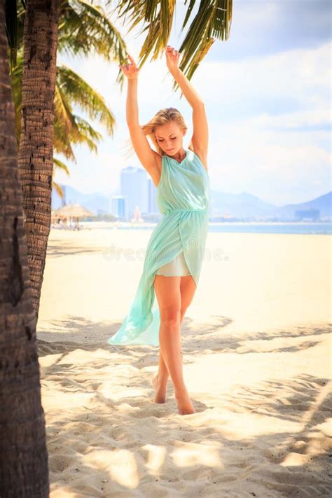 Blonde Girl In Azure With Hands On Breast Near Palms On Beach Stock