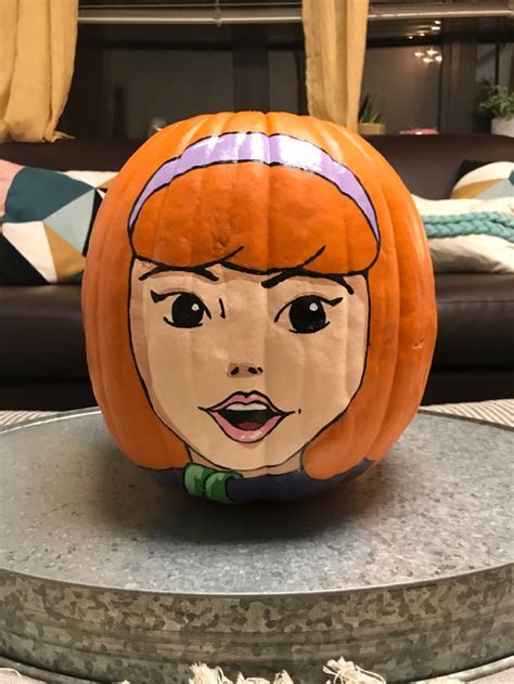 A Pumpkin With A Face Painted On It In The Shape Of A Woman S Head