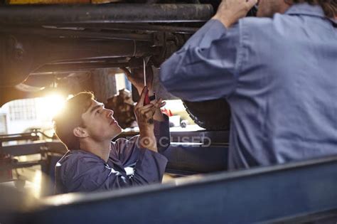 Mechanics Working Under Car In Auto Repair Shop — Expertise Tool