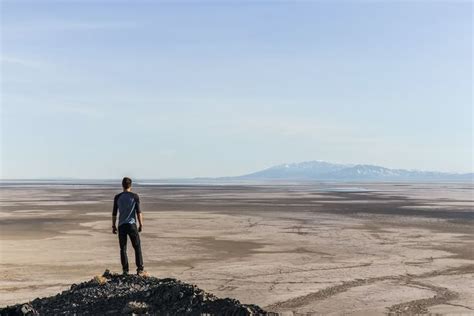 Man Standing On Top Of Mountain Overlooking Desert During Daytime Photo