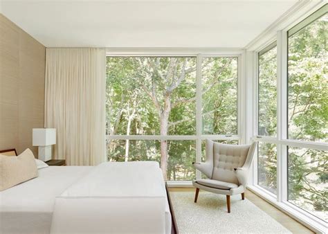 A White Bedroom With Large Windows Looking At Trees Home Home Decor