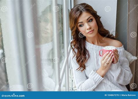 A Beautiful Slender And Brunette Girl Sits Near A Large Win Stock Photo