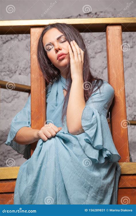 Sad Beautiful Woman In Blue Dress Posing In Studio With Wooden Ship