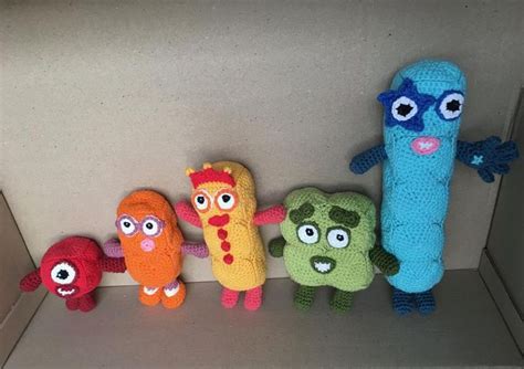 Five Crocheted Toy Characters Are Lined Up In A Row On A Shelf