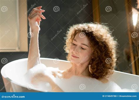Attractive Caucasian Woman Soaks In The Bath And Looks At The Foam On Her Hands A Photograph Of