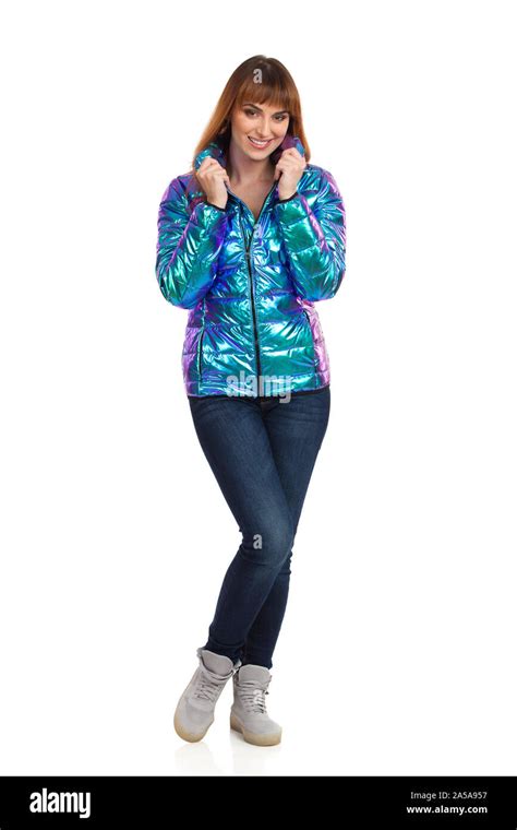 Young Woman In Vibrant And Shiny Down Jacket Jeans And Sneakers Is