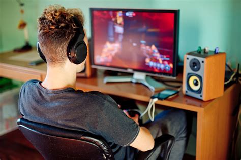 Teen Boy Playing Games On Computer Wearing Headphones Stock Photo