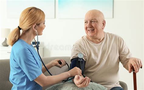 Nurse Measuring Blood Pressure Of Elderly Man Assisting Senior People