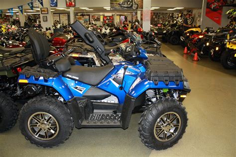 A Blue Four Wheeler Is Parked In A Showroom With Other Vehicles And
