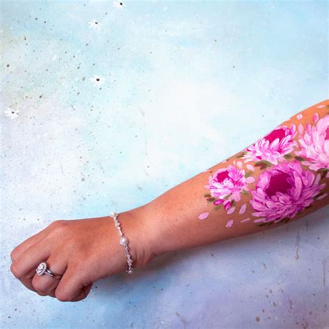 A Womans Arm With Pink Flowers Painted On It And A Diamond Ring In The