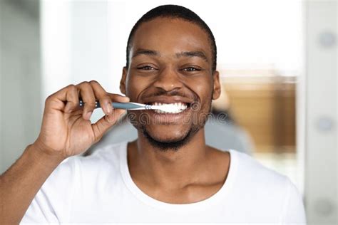 Joyful African American Guy Brushing Teeth With Toothbrush At Home