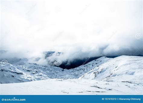The Stunning Landscape Of The Snowy Mountain On A Foggy Misty Cloudy