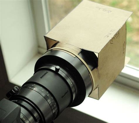 A Camera Lens Sitting In Front Of A Box On A Window Sill With The Lid Open