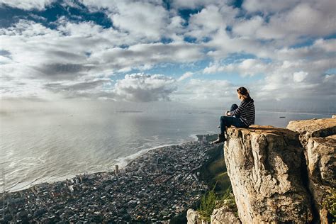 Woman Sitting On The Edge Of A Cliff Overlooking Cape Town At Sunset By Stocksy Contributor