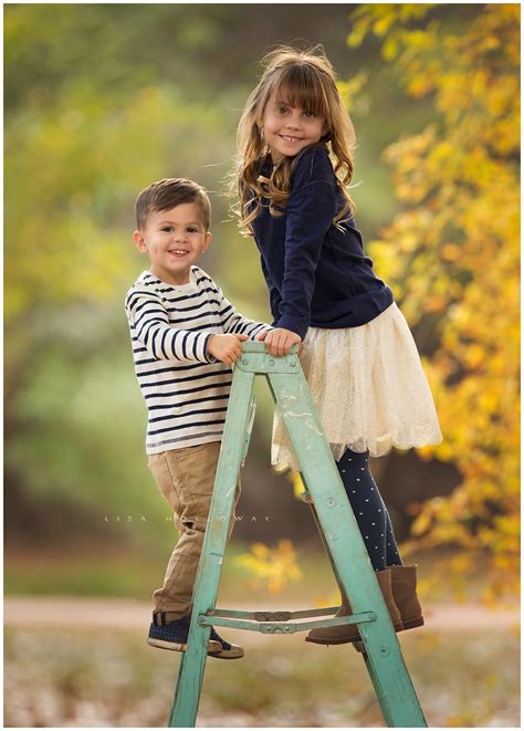 Adorable Brother And Sister Pose On A Blue Wooden Ladder For An Outdoor