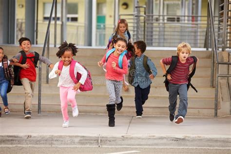 A Group Of Elementary School Kids Rushing Out Of School Stock Image