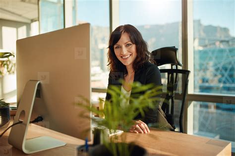 Smiling Female Entrepreneur Sitting At Her Desk Stock Photo 130311