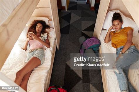 Young Woman Checking Phone In Bunk Bed Roommate Sleeping In The Other