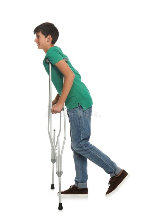 Teenage Boy With Injured Leg Using Crutches On White Background Stock