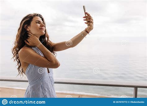 Nice Young Caucasian Girl Stands On Hotel Balcony And Takes Selfie On